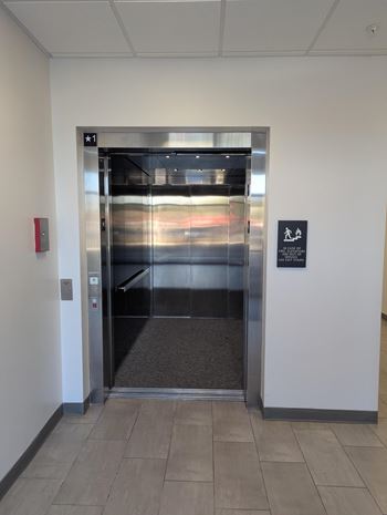 A silver elevator with a black sign on the wall.